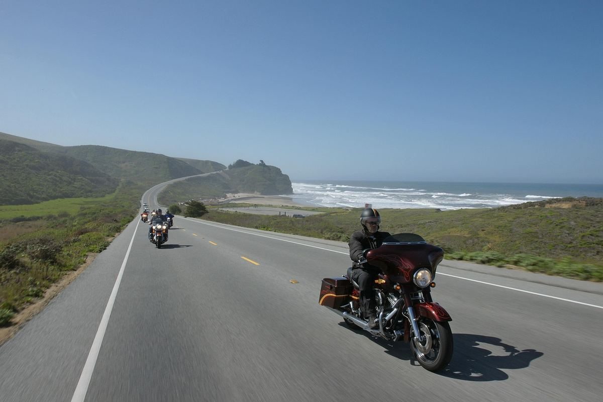 Motards circulant sur route côtière sinueuse surplombant l'océan et falaises vertes