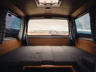 Intérieur d'un véhicule camper avec lit pliant, rideaux et vue extérieure